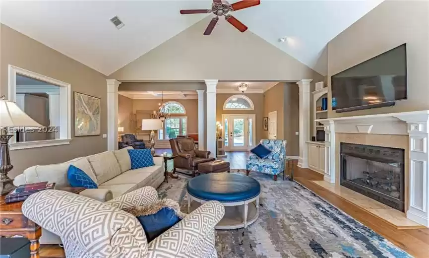 Living room with ornamental molding, ceiling fan, light hardwood / wood floors, high vaulted ceiling, and ornate columns