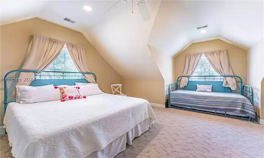 Bedroom with multiple windows, light colored carpet, lofted ceiling, and ceiling fan