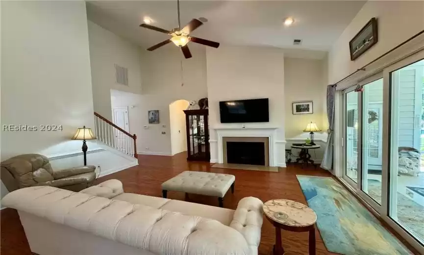 Living room with ceiling fan, a high ceiling, and dark hardwood / wood-style floors