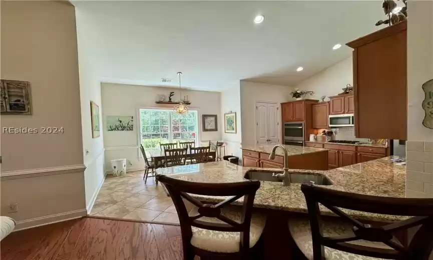 Dining area featuring a notable chandelier, lofted ceiling, sink, and light tile floors