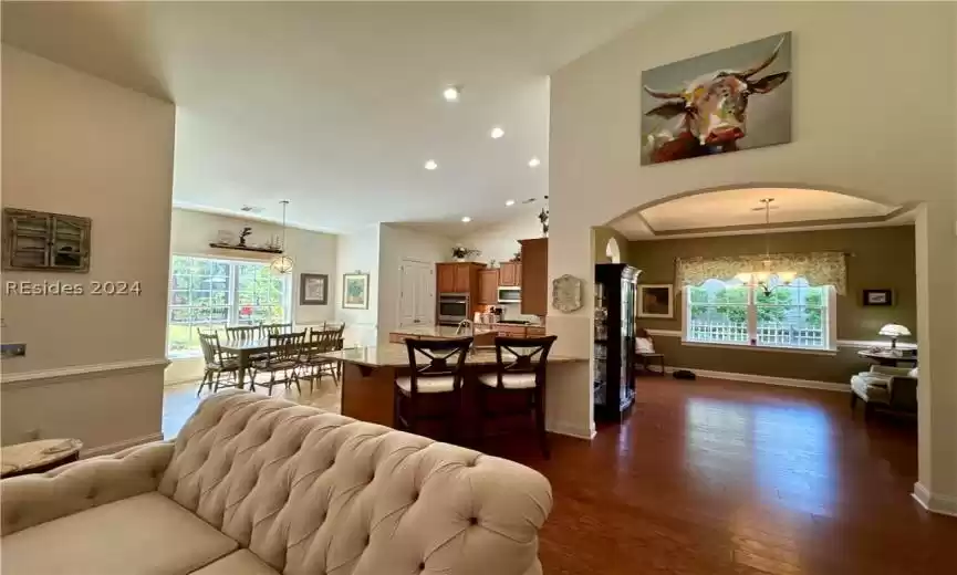 Living room with an inviting chandelier, dark wood-type flooring, and high vaulted ceiling