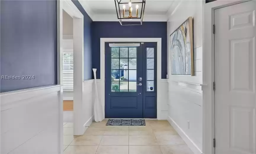 Entryway with a chandelier, ornamental molding, and light tile floors
