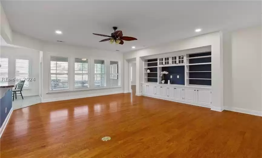 Unfurnished living room featuring light wood-type flooring, built in shelves, and ceiling fan