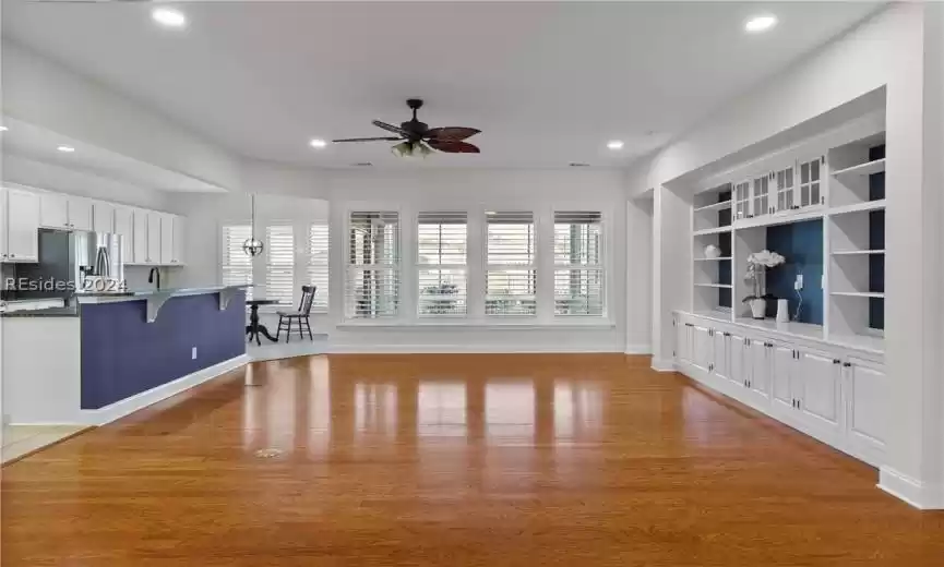 Unfurnished living room with built in shelves, light hardwood / wood-style flooring, sink, and ceiling fan