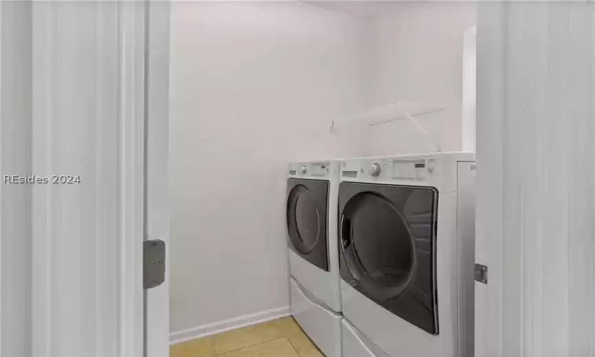 Washroom featuring light tile floors and washer and dryer