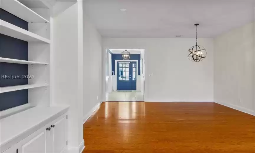 Spare room with a notable chandelier, light hardwood / wood-style flooring, and built in features