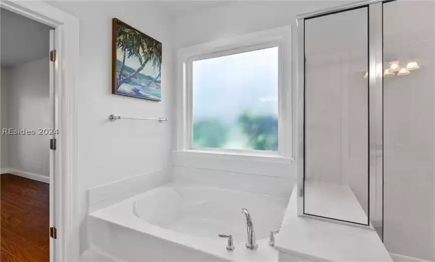 Bathroom featuring shower with separate bathtub, a healthy amount of sunlight, and wood-type flooring
