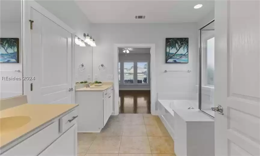 Bathroom with dual bowl vanity, a bath to relax in, and tile flooring