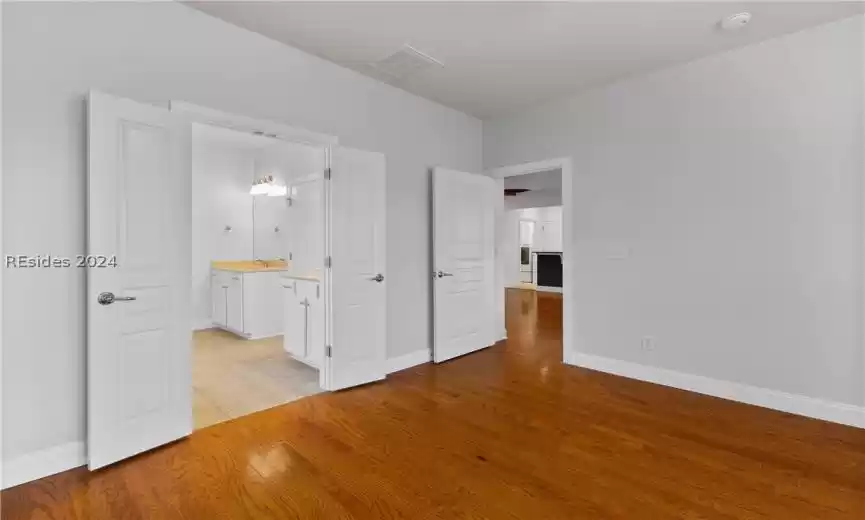 Unfurnished bedroom featuring ensuite bathroom, sink, and light hardwood / wood-style floors