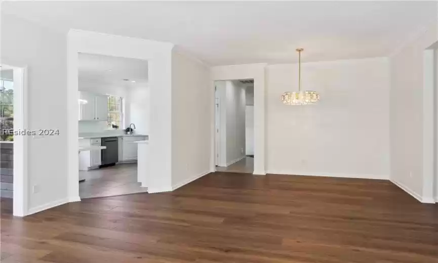 Empty room with a chandelier, a textured ceiling, and dark wood-type flooring