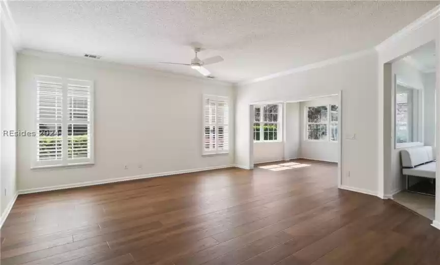Unfurnished room with dark hardwood / wood-style flooring, ceiling fan, ornamental molding, and a healthy amount of sunlight