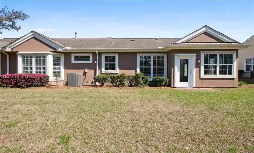 Back of property featuring central AC unit and a lawn