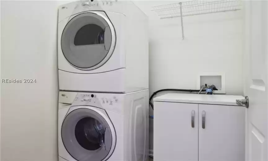 Laundry room featuring hookup for a washing machine, cabinets, and stacked washer / dryer