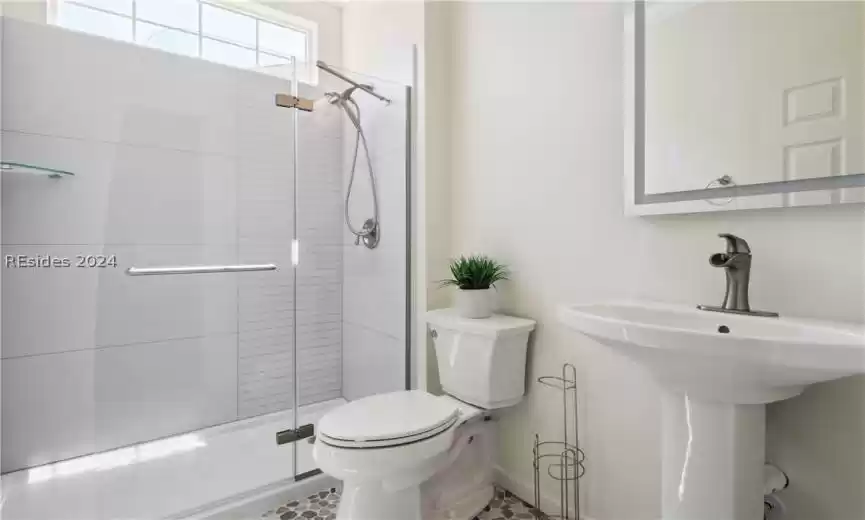 Bathroom featuring tile flooring, toilet, a shower with shower door, and a healthy amount of sunlight