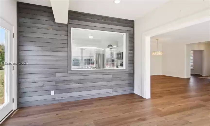 Empty room with a chandelier, wood walls, and dark hardwood / wood-style floors
