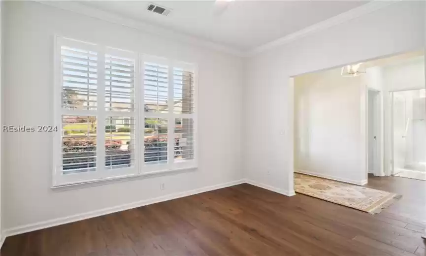 Unfurnished room featuring a notable chandelier, crown molding, and dark hardwood / wood-style floors