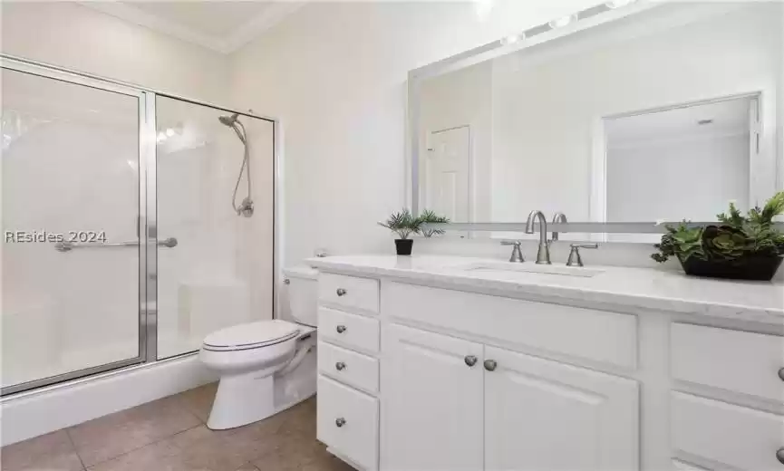 Bathroom featuring an enclosed shower, vanity, crown molding, toilet, and tile flooring