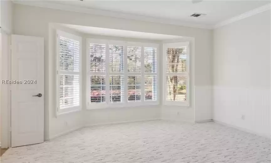 Spare room with light colored carpet, ornamental molding, and a healthy amount of sunlight