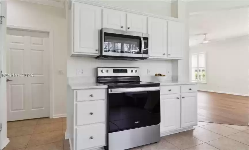 Kitchen with white cabinets, ceiling fan, light hardwood / wood-style flooring, ornamental molding, and stainless steel appliances