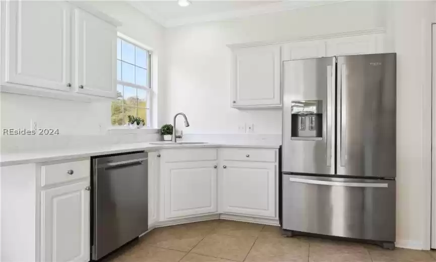 Kitchen featuring ornamental molding, stainless steel appliances, white cabinetry, and light stone counters