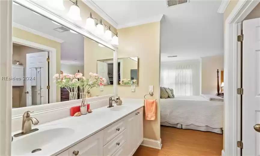 Bathroom with wood-type flooring, double vanity, and crown molding