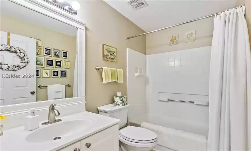Full bathroom near bedroom 3, featuring shower / bath combo, toilet, vanity, and mirror with custom molding trim.