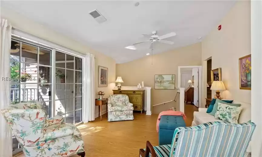Living room with sliding glass doors that lead out to lovely sunny enclosed porch with railing.