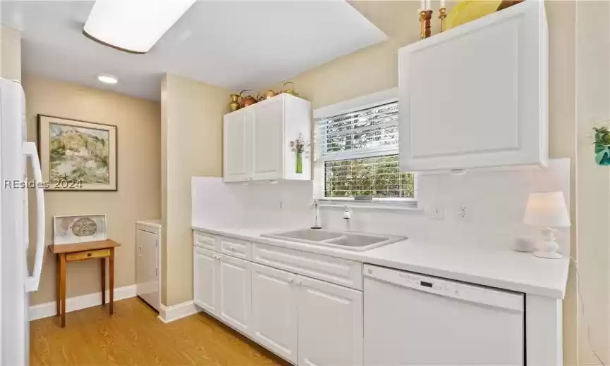 Kitchen featuring white appliances, tasteful backsplash, sink, light hardwood / wood-style flooring, and white cabinets