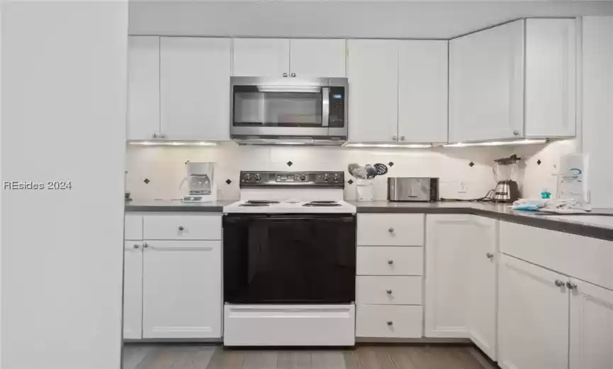 Bright kitchen with under cabinet lighting and all the kitchen supplies you need.