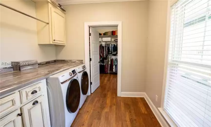Combined laundry/mudroom complete with cabinets and a hanging rack, which leads directly into the closet of the primary bedroom
