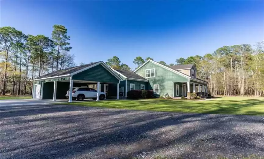 View of front of home featuring covered porch, a front yard, and a garage