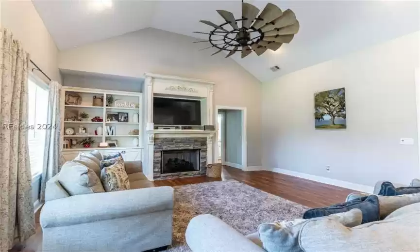 Living room with a gas stone fireplace and vaulted ceiling.