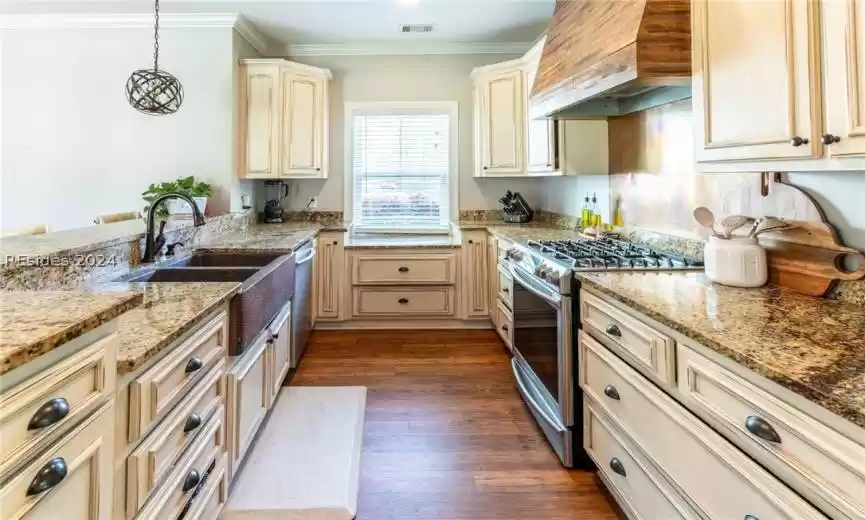Kitchen featuring granite counters, hammered copper sink, pendant lighting, stainless steel appliances, and premium range hood.