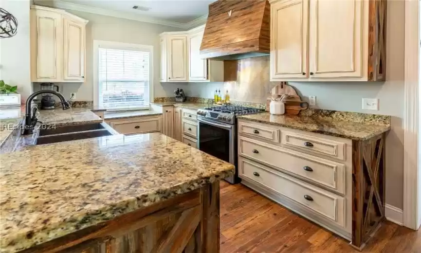 Kitchen with gas range, granite countertops, and custom exhaust hood.