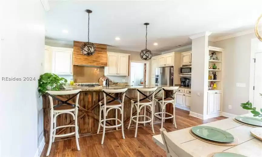 Kitchen featuring stainless steel appliances, decorative light fixtures, and cream cabinets