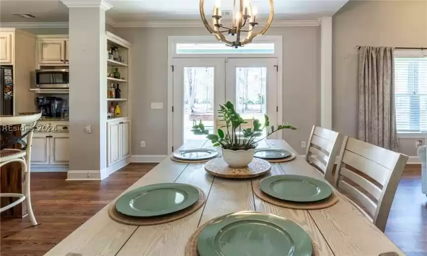 Dining room featuring plenty of natural light, an inviting chandelier, crown molding, with french doors leading to the back patio.