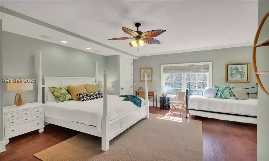 Bedroom with ceiling fan, crown molding, and wood flooring