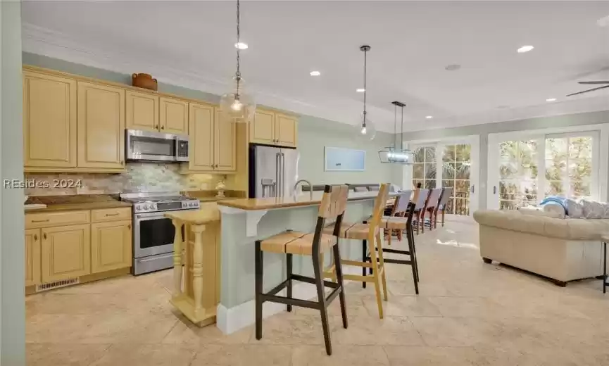 Kitchen featuring crown molding, a kitchen breakfast bar, pendant lighting, granite and SS appliances