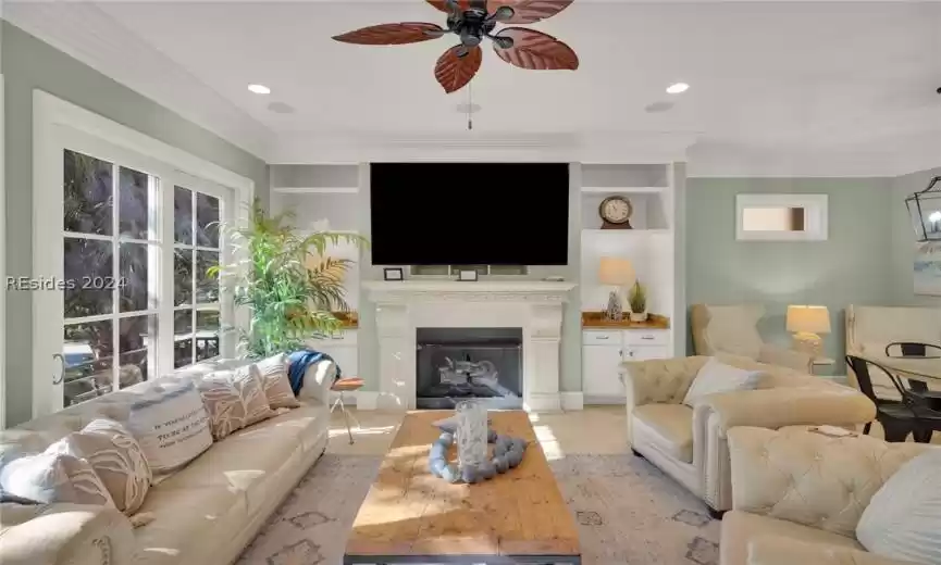 Living room featuring ceiling fan, built in features, and crown molding