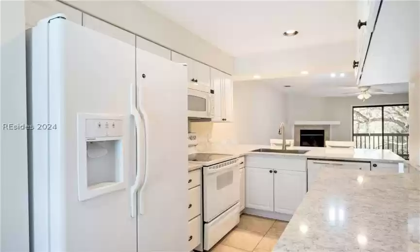 Brand new stainless steel sink, extra cabinets, smooth ceilings, white appliances and Cambria quartz counters with view of living area.