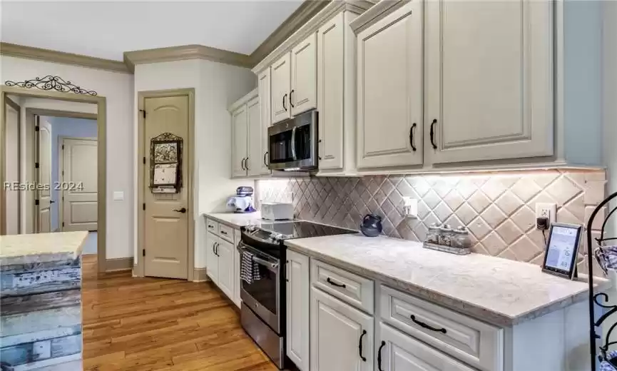 Another look at this wonderful kitchen with gleaming wood floors and attractive stone counters, tile backsplash and large pantry.