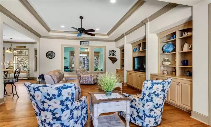 Open concept family room/living room with gleaming wood floors, tray ceiling and beautiful built-in cabinetry and shelving. (Length of wall custom built-ins for excellent storage).