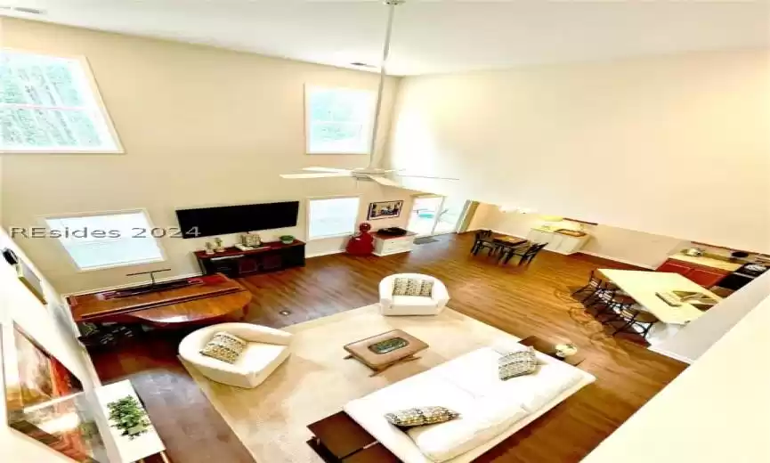 Living room with hardwood / wood-style floors, ceiling fan, and high vaulted ceiling
