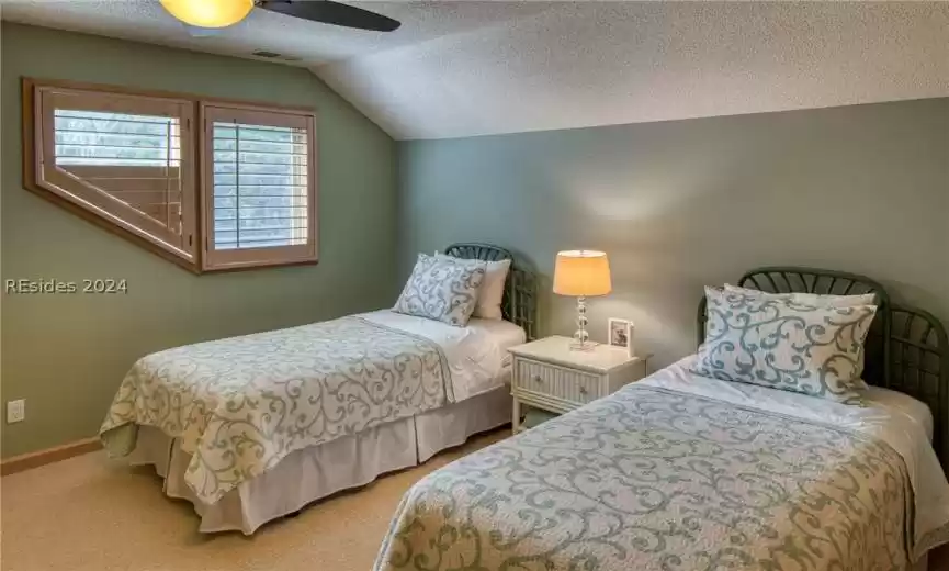 Carpeted bedroom with lofted ceiling, ceiling fan, and a textured ceiling