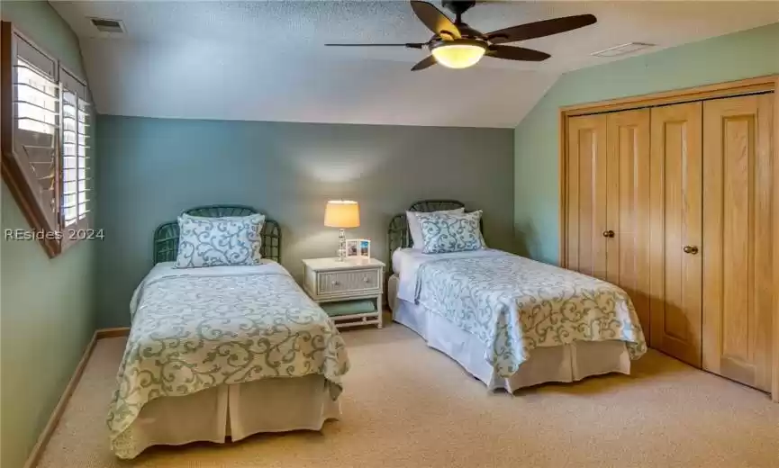 Bedroom featuring a closet, ceiling fan, a textured ceiling, vaulted ceiling, and light colored carpet