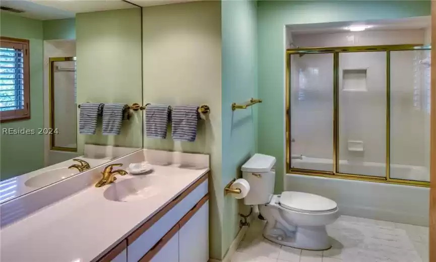 Full bathroom featuring combined bath / shower with glass door, tile flooring, a textured ceiling, vanity with extensive cabinet space, and toilet