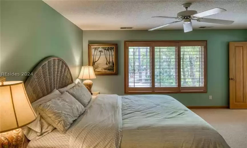 Carpeted bedroom featuring a textured ceiling and ceiling fan