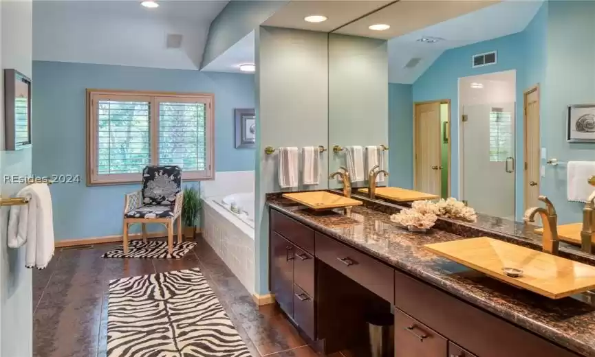 Bathroom featuring oversized vanity, dual sinks, lofted ceiling, plus walk in shower, and tile floors