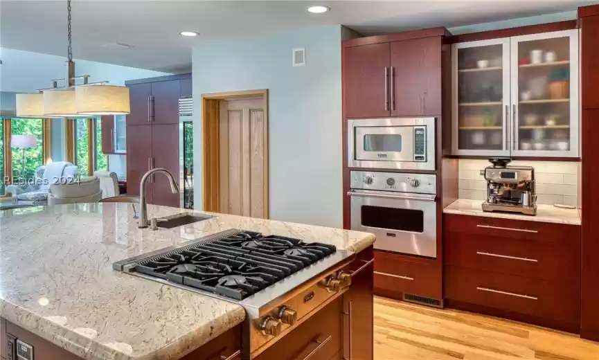 Kitchen featuring light stone countertops, backsplash, light hardwood / wood-style floors, sink, and stainless steel appliances