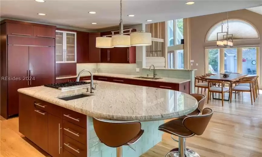Kitchen with backsplash, a center island with sink, light wood-type flooring, and sink